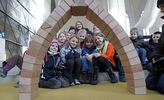 Symbolbild zur Unterseite für Besucher: zeigt Kindergruppe hinter einen gotischen Bogen aus Holzbausteinen